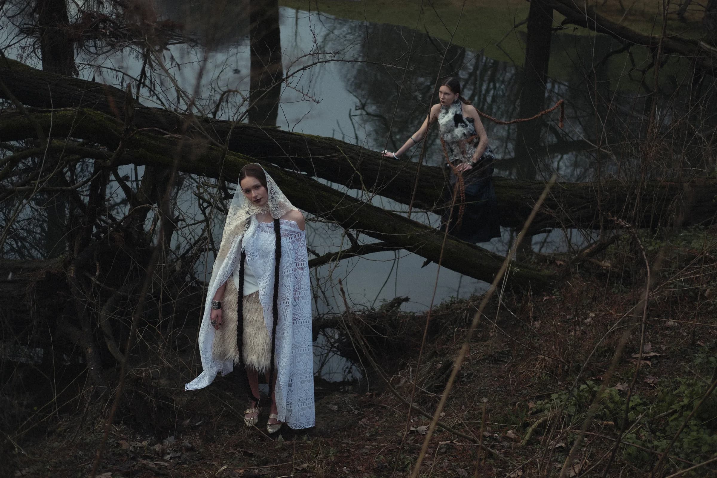 Two figures in a dark forest wearing folkloric garments