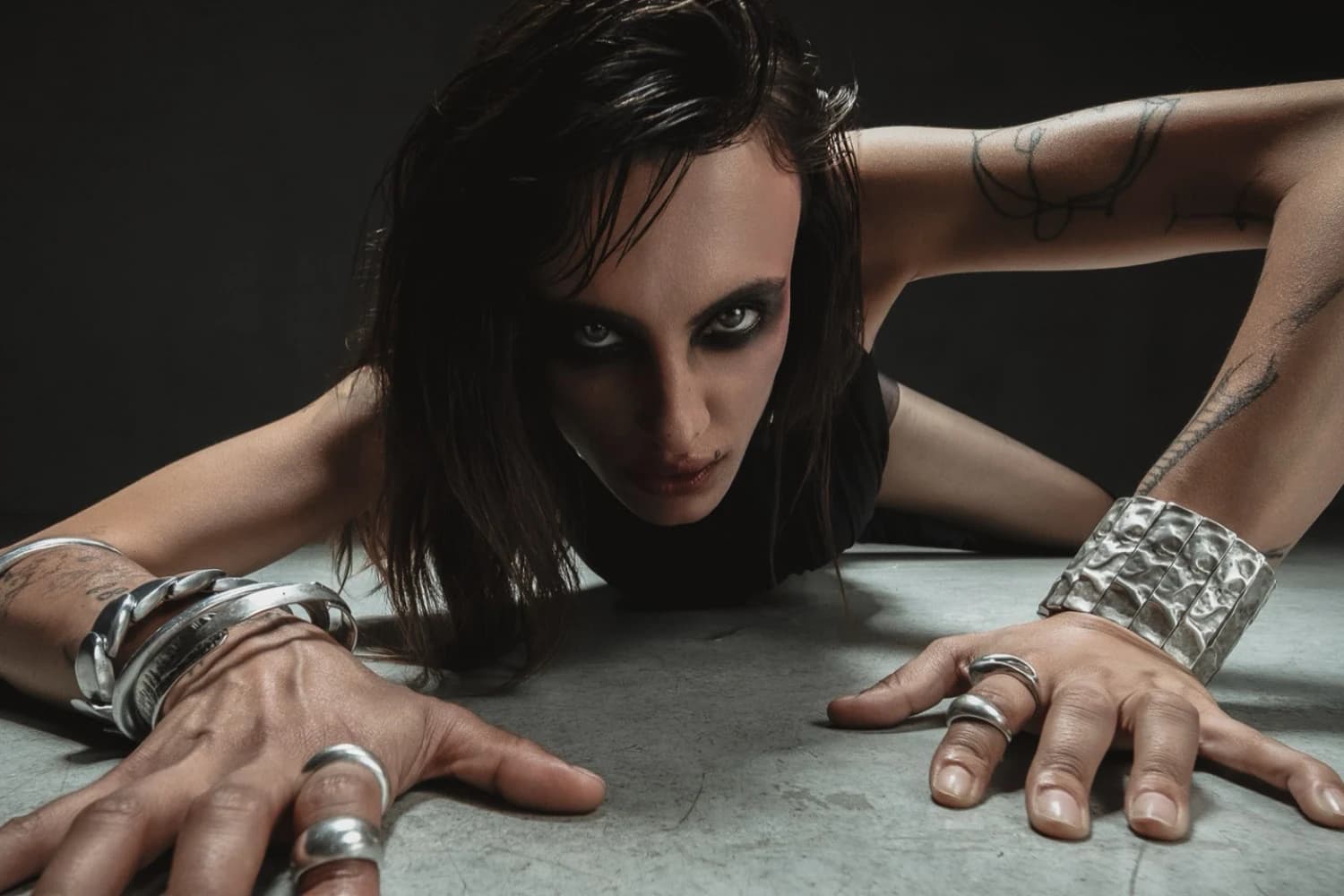 Model leaning forward with metallic jewellery in a dark editorial portrait